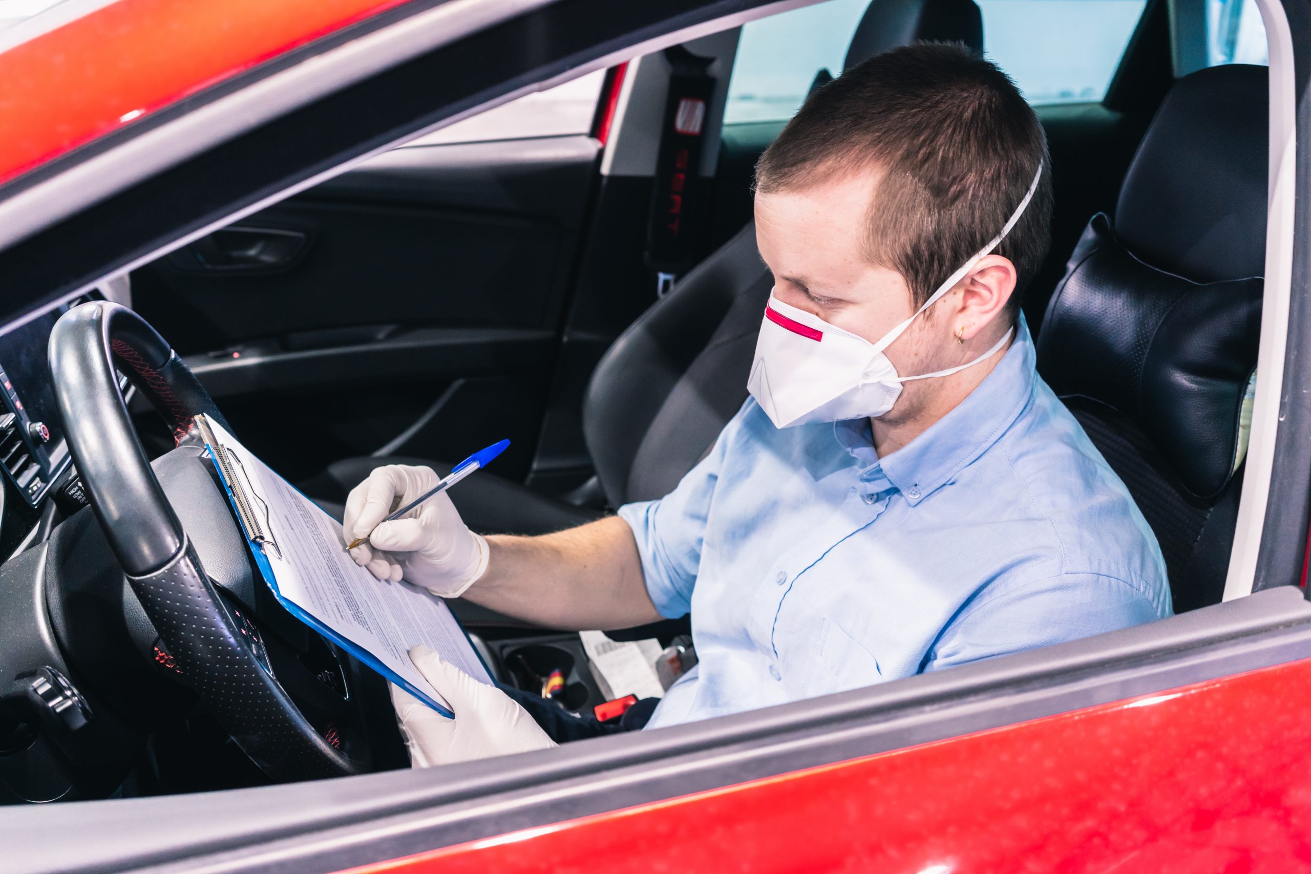 Technician doing a security inspection inside a vehicle protected with a mask and gloves to prevent the spread of virus